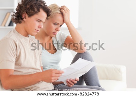 Despaired couple reading letters in the living room