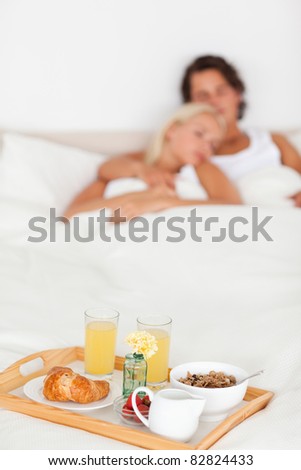 Breakfast on a tray with a couple sleeping with the camera focus on the foreground