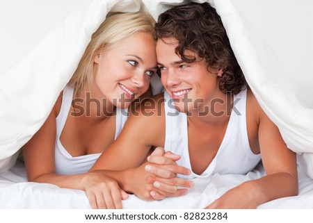 Portrait of an in love couple under a duvet in a bed