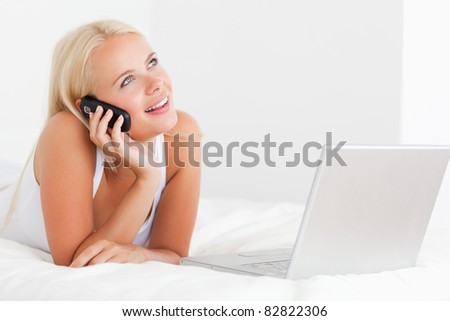Woman on the phone with a laptop in her bedroom
