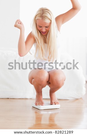 Portrait of a cheerful woman squatting on a weighing machine