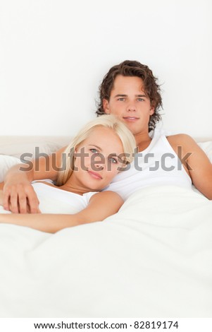 Cute couple lying on a bed while looking at the camera