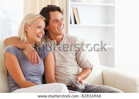 Laughing couple watching TV in their living room