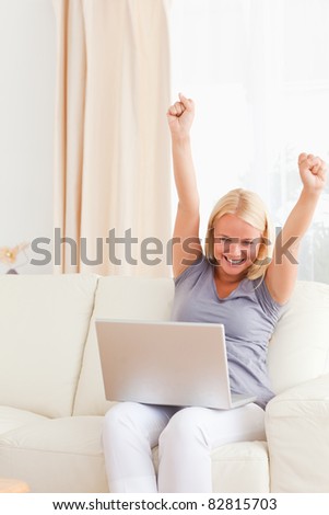 Woman cheering up while using a laptop in her living room