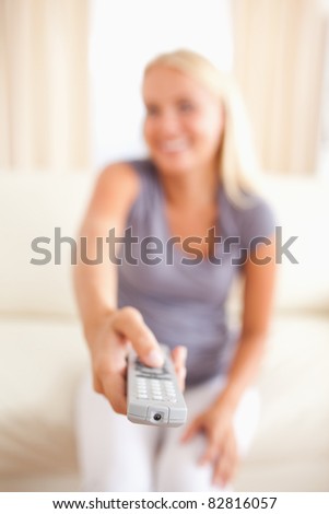 Portrait of a smiling woman watching TV with the camera focus on the remote