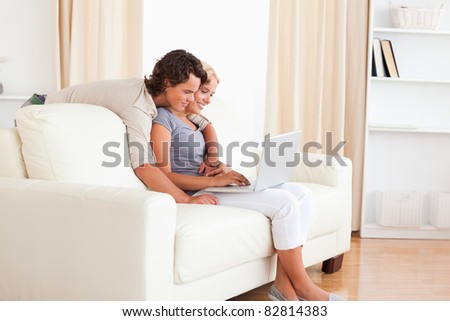 Smiling young couple using a notebook in their living room