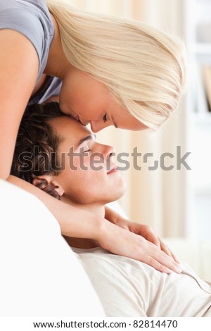 Portrait of a woman kissing her fiance on the forehead in their living room