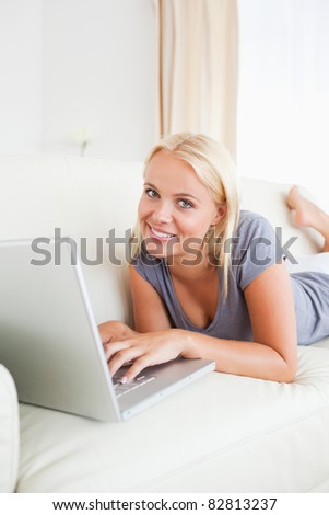 Portrait of a lying woman using a notebook in her living room
