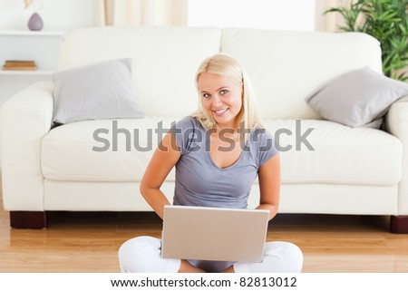 Happy woman with a notebook while sitting on the floor in her living room