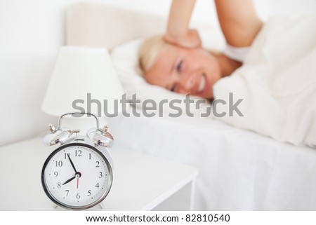 Angry woman awaken by her alarm clock in her bedroom