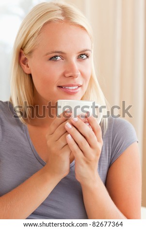 Portrait of a calm woman sitting on a couch with a cup of tea looking at the camera