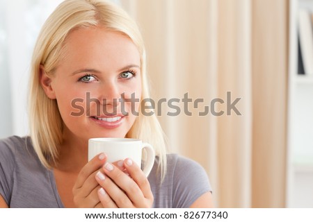 Calm woman sitting on a couch with a cup of tea in her livng room