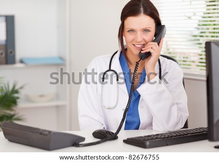 A female doctor is telephoning in an office