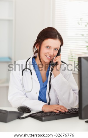 A female doctor is telephoning and looking to the camera