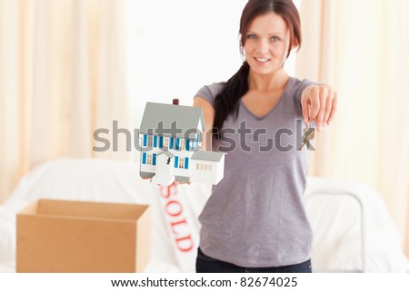Beautiful woman holding model house and keys in a living room