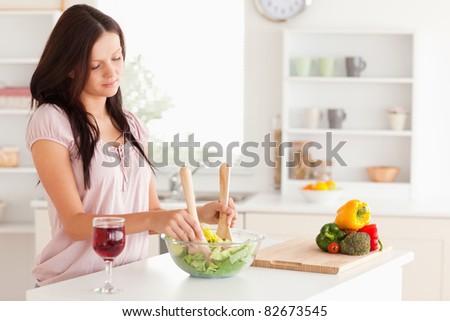 Young woman mixing a salad in a kitchen