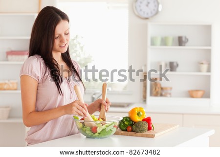 Cute woman mixing a salad in a kitchen