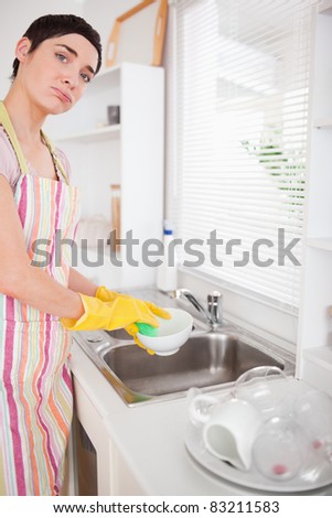 Sad woman washing the dishes in the kitchen