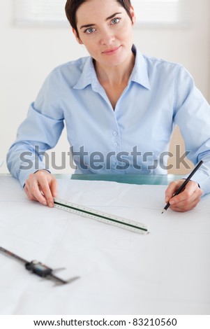 Gorgeous Woman working on an architectural plan looking into the camera in an office