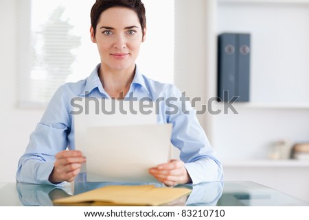 Portrait of a brunette Businesswoman sitting behind a desk with papers in an office