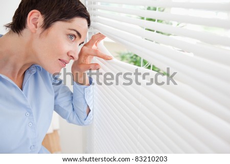 Good-looking brunette woman peeking out a window in an office