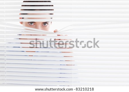 Curious cute Woman peeking out of a window in an office