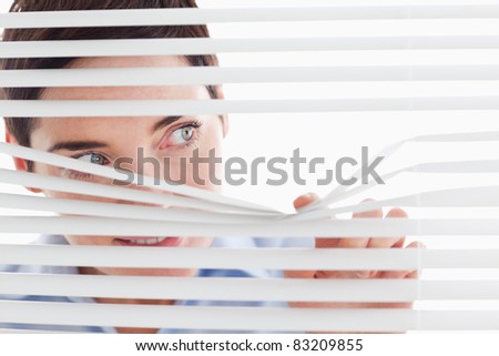 Charming businesswoman peeking through a venetian blind in an office