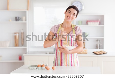 Charming brunette woman preparing a cake in a kitchen