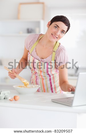 Smiling Woman looking at a receipt on a laptop in a kitchen