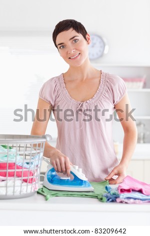 Smiling Woman ironing clothes in a utility room