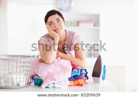 Bored Woman with a pile of clothes in a utility room
