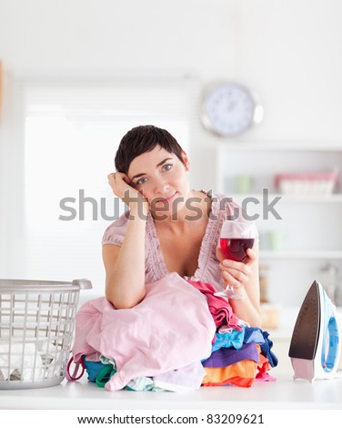 Brunette Woman with wine and a pile of clothes in a utility room