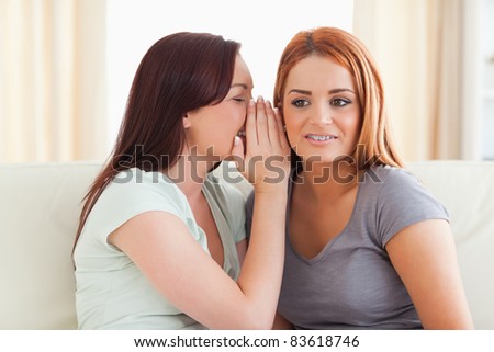 Young woman being told a secret in a living room