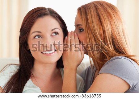 Gorgeous woman being told a secret in a living room