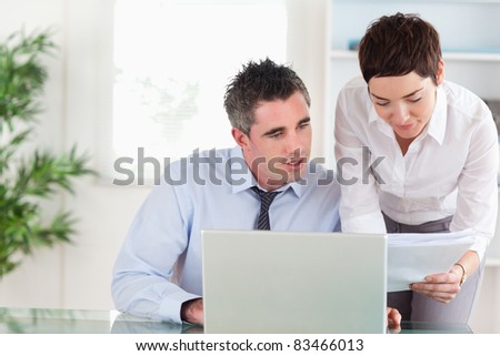 Coworkers comparing a blueprint document to an electronic one in an office