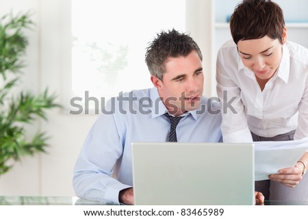Office workers comparing a blueprint document to an electronic one in an office