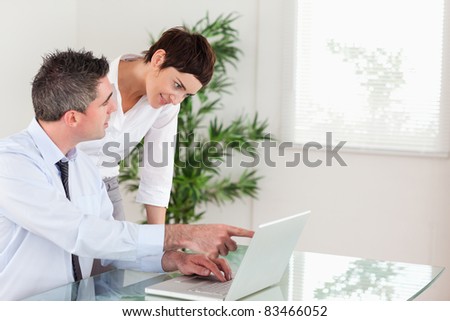 Man pointing at something to his colleague on a laptop in an office