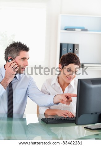 Portrait of a man showing something to his coworker on a computer in an office