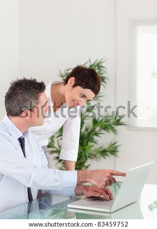 Portrait of a man pointing at something to his colleague on a laptop in an office