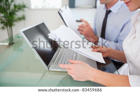 Managers typing a report from blueprint documents in an office