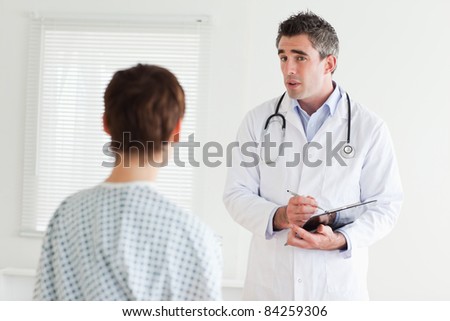 Serious Doctor talking to a woman in hospital gown in a room