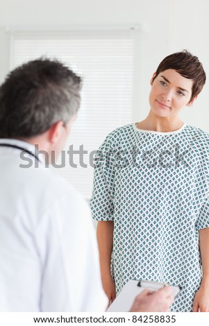 Cute Woman in hospital gown talking to her doctor in a room