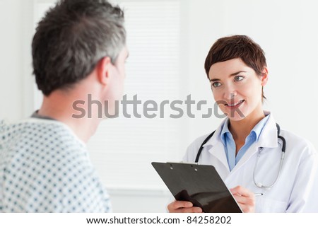 Doctor talking to a male patient holding a chart in a room