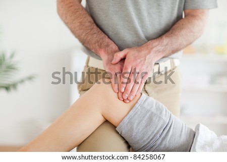 Chiropractor massaging a charming woman\'s knee in a room