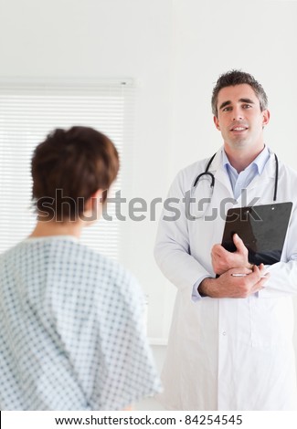 Doctor talking to a charming woman in hospital gown in a room