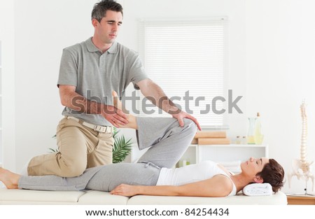 A chiropractor is stretching a customer\'s leg