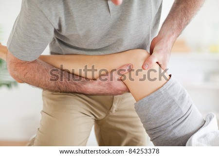 Chiropractor massaging a patient\'s knee in a room