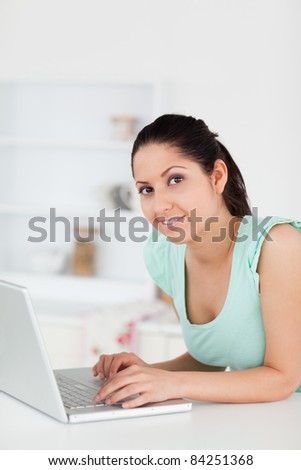 A young woman standing at her laptop looking to camera