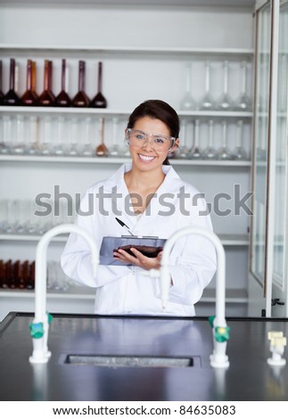Portrait of a student in science writing on a clipboard in a laboratory