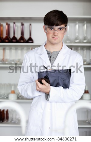 Portrait of a male science student writing on a clipboard in a laboratory
